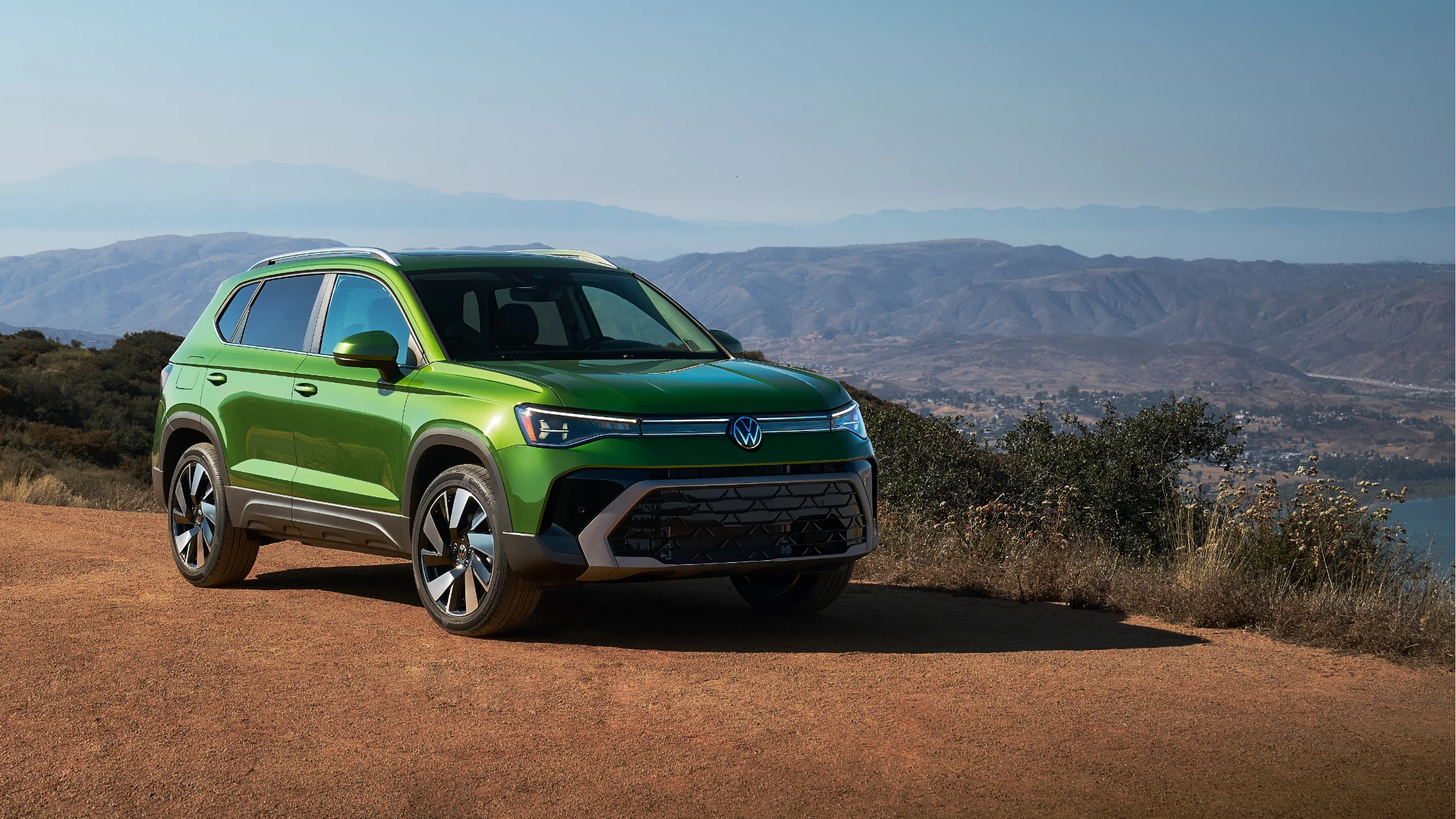 2025 Volkswagen Taos SUV parked on a hill with a scenic mountain backdrop.
