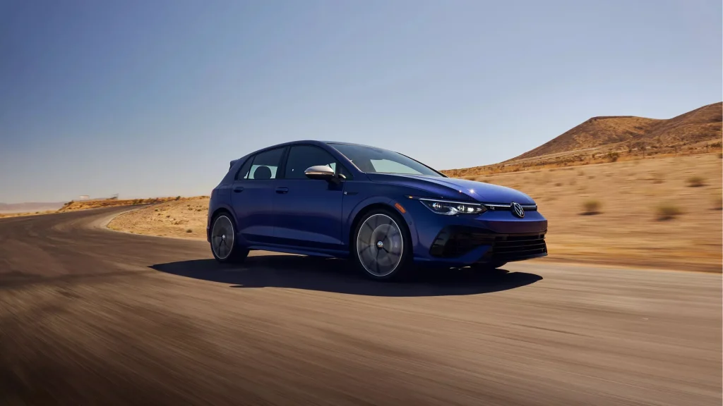 A blue 2025 Volkswagen Golf R driving on a curvy desert road.