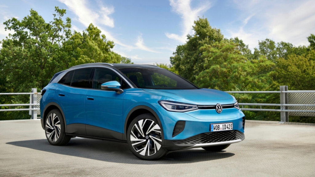 2025 Volkswagen ID.4 electric van in orange and white driving on an open countryside highway.