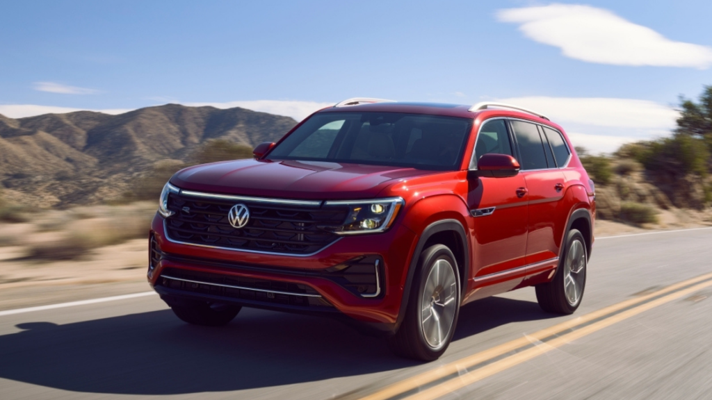 2026 Volkswagen Atlas in red SUV driving on highway with rugged style and chrome accents.