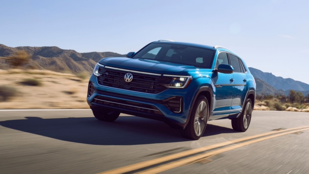2026 Volkswagen Atlas Cross Sport in blue SUV driving on desert road with bold front fascia.
