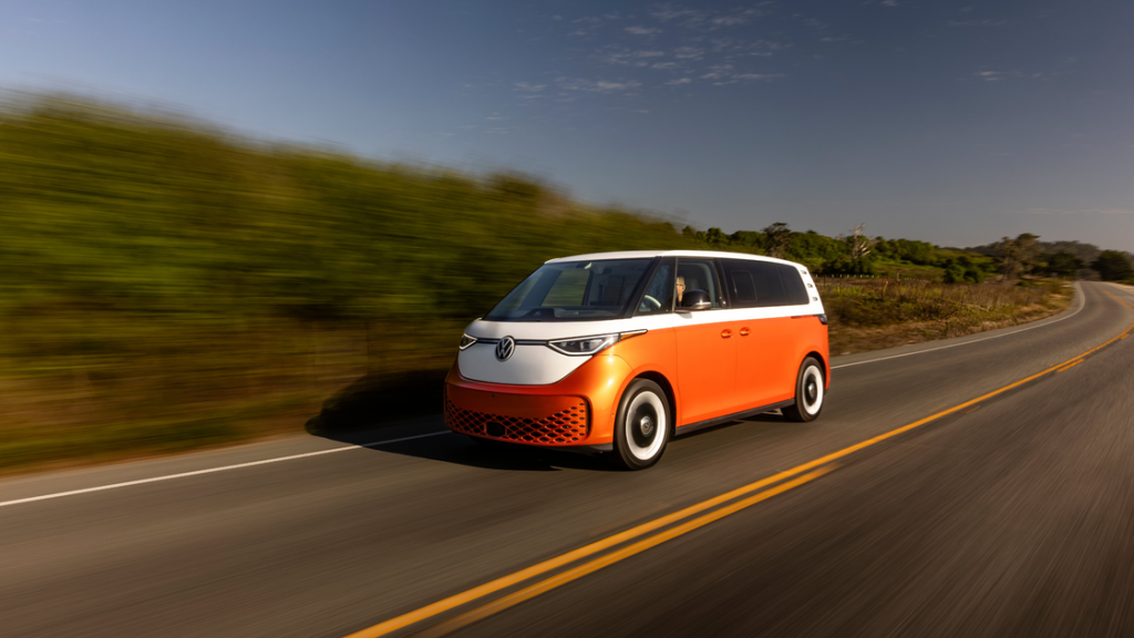 2025 Volkswagen ID. Buzz electric van driving on open road with two tone orange and white exterior.