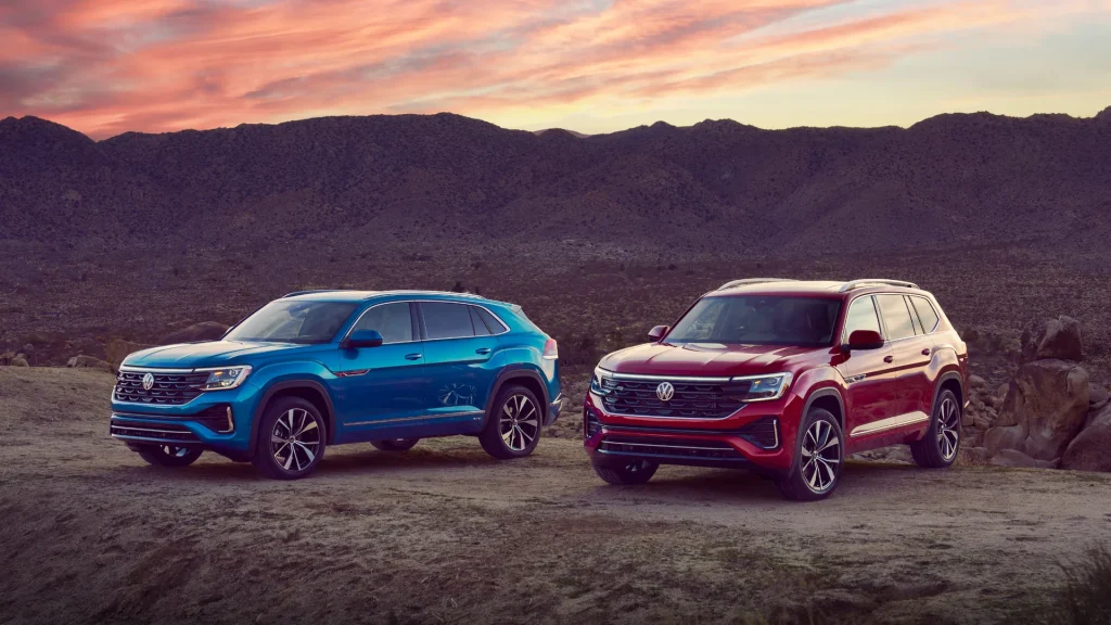 Two 2026 Volkswagen Atlas Cross Sport SUVs parked on a desert overlook at sunset.