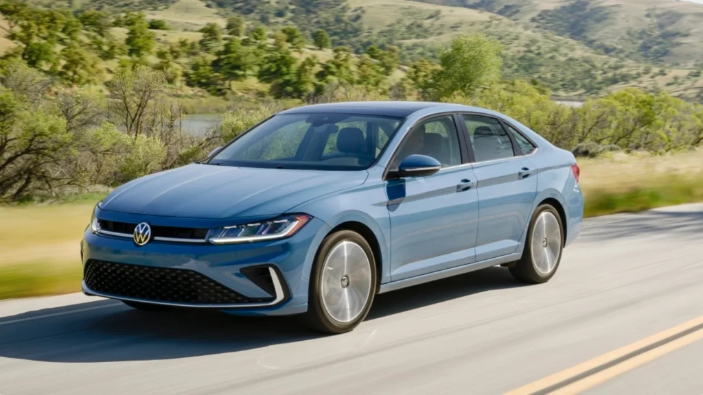 2026 Volkswagen Jetta sedan driving on a scenic road in front three quarter view.