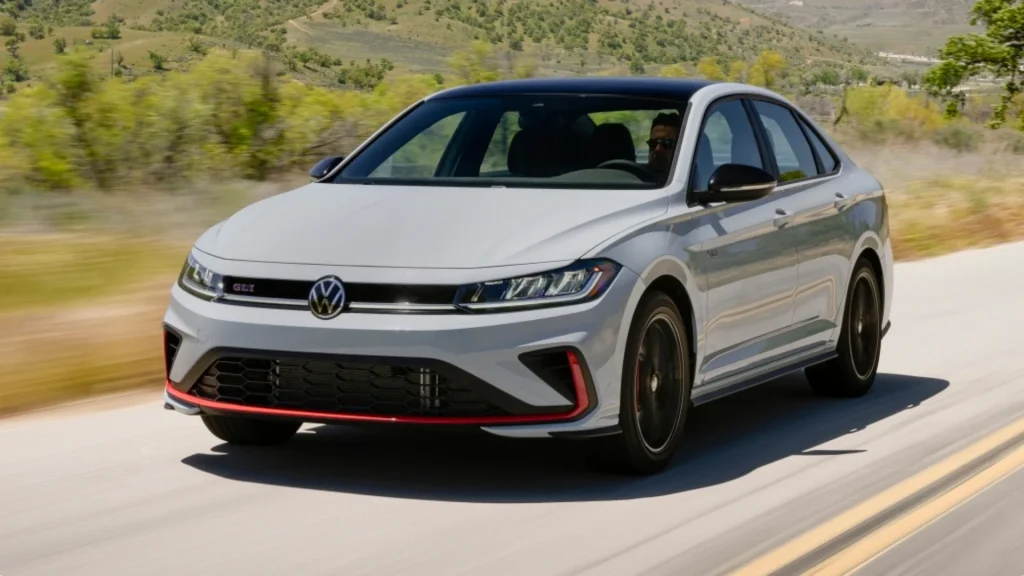 2026 Volkswagen Jetta GLI driving on a scenic road in front three quarter view.