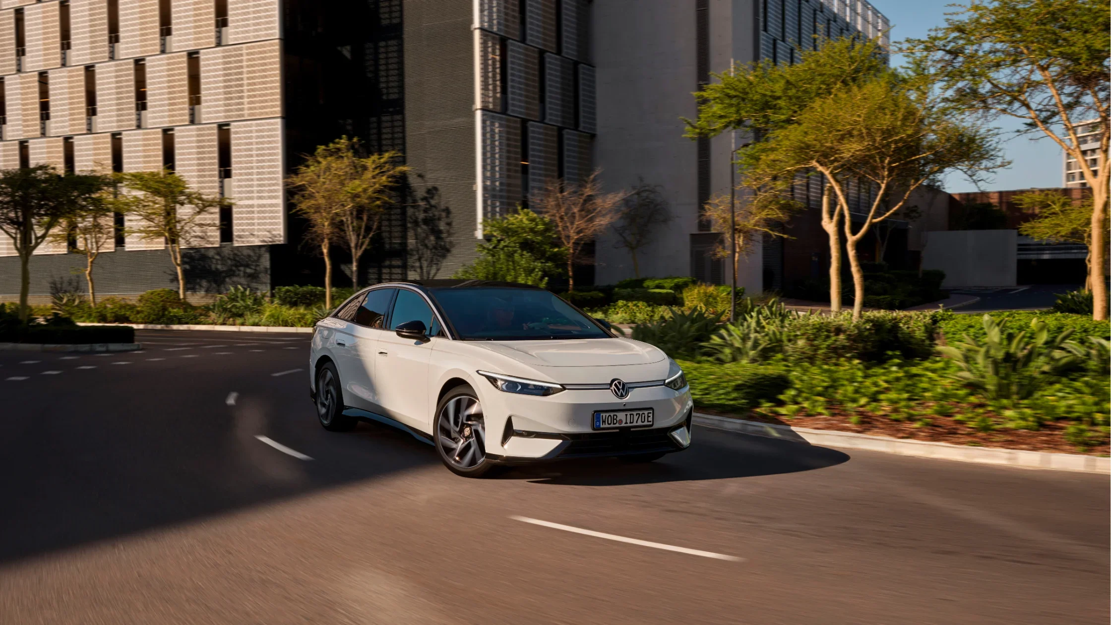 2025 Volkswagen ID.7 driving through a modern cityscape in sunlight.