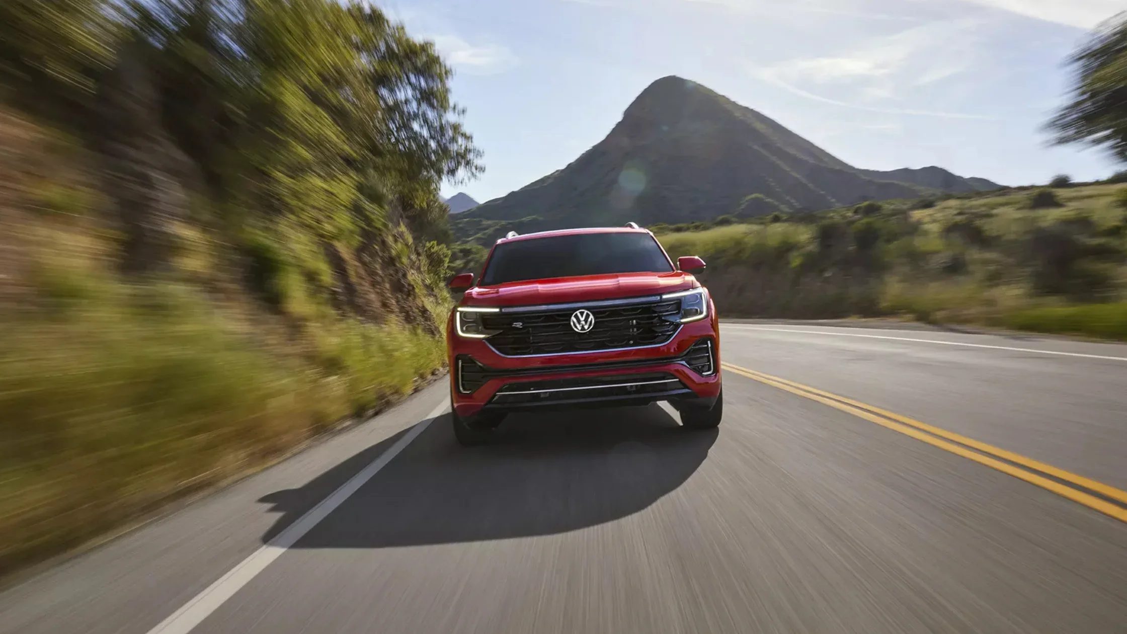 Front view of red 2025 Volkswagen Atlas driving on scenic mountain road