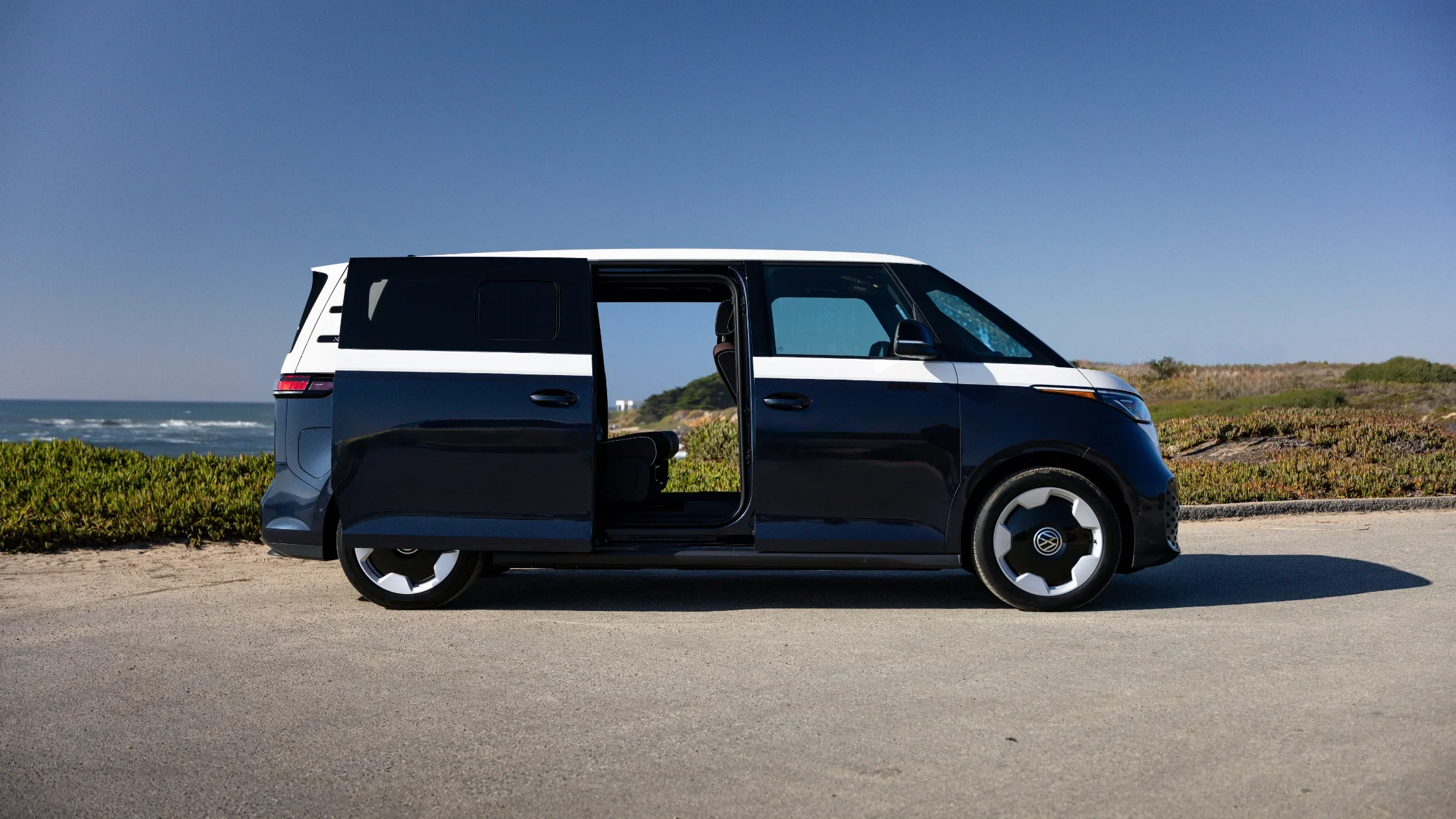 Side view of the 2025 Volkswagen ID. Buzz with sliding door open near the ocean