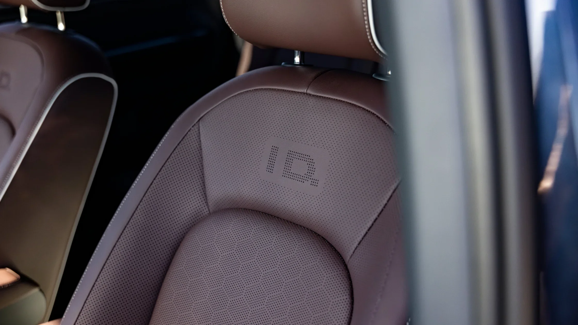 Close-up of brown leather seat with embossed IQ badge in the 2025 Volkswagen ID. Buzz interior