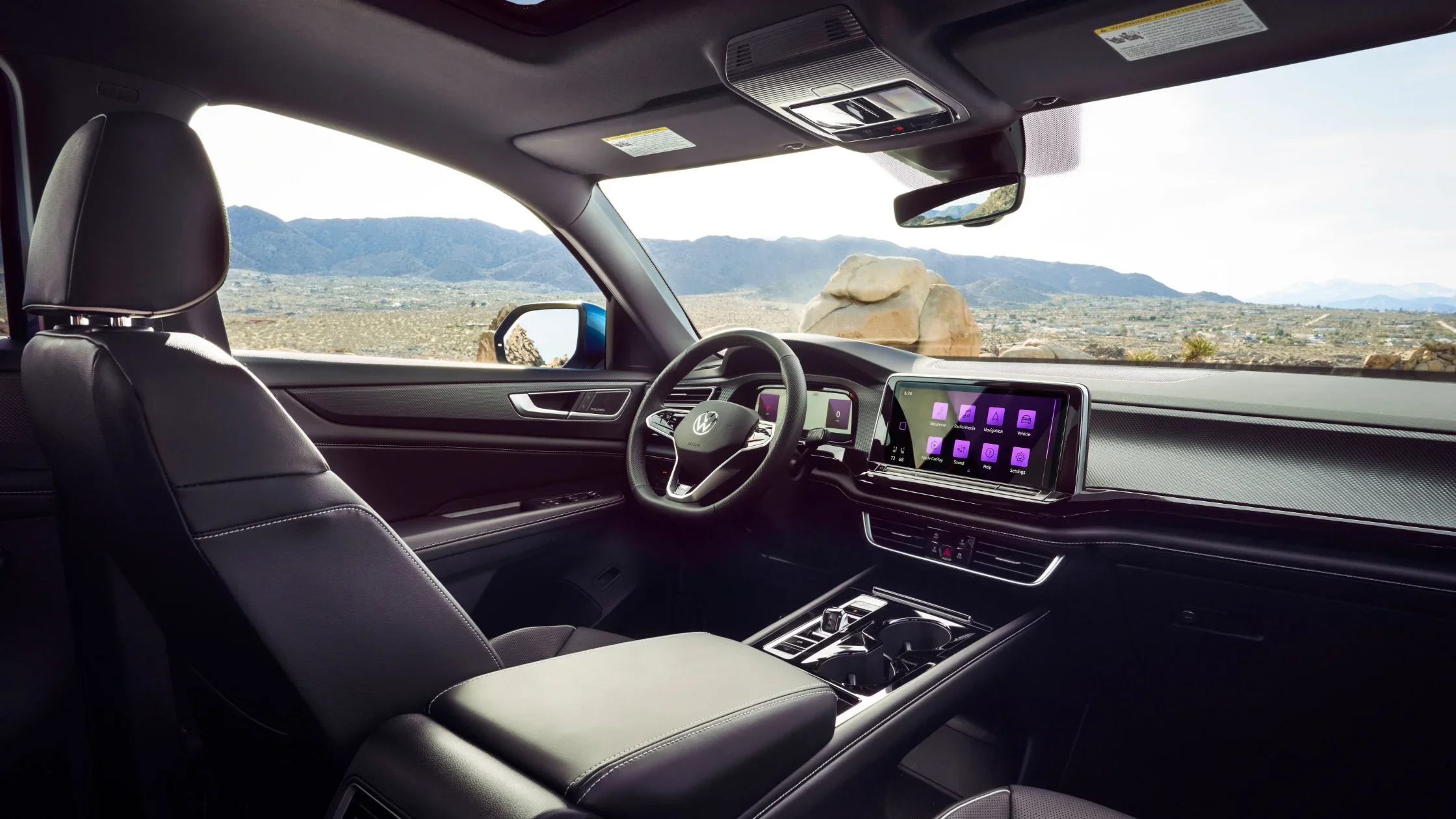 Interior view of the 2025 Volkswagen Atlas Cross Sport featuring a modern dashboard with digital display and scenic mountain background through the windshield.
