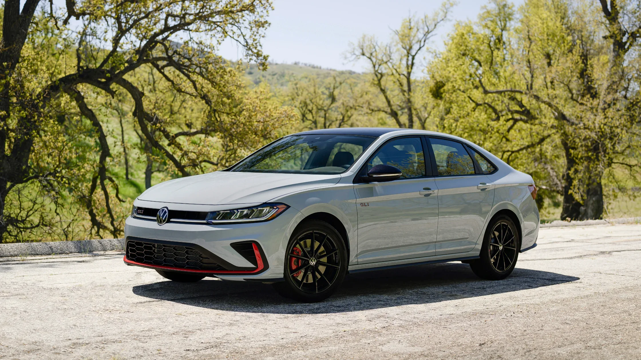 Front profile of the sporty 2026 Volkswagen Jetta GLI sedan with red trim accents and alloy wheels.