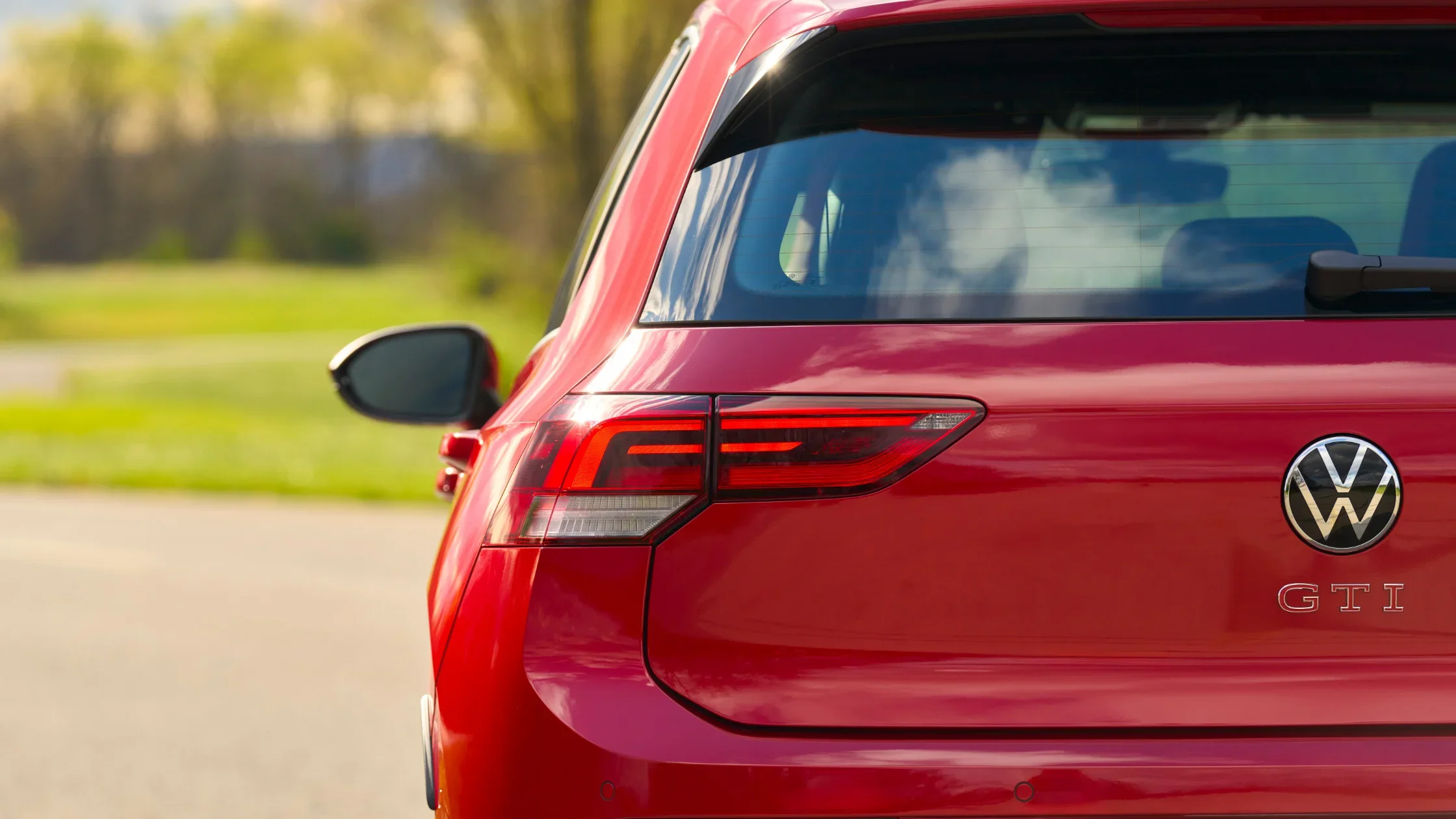 Rear view of red 2025 Volkswagen Golf GTI showing taillight and GTI badging in daylight.