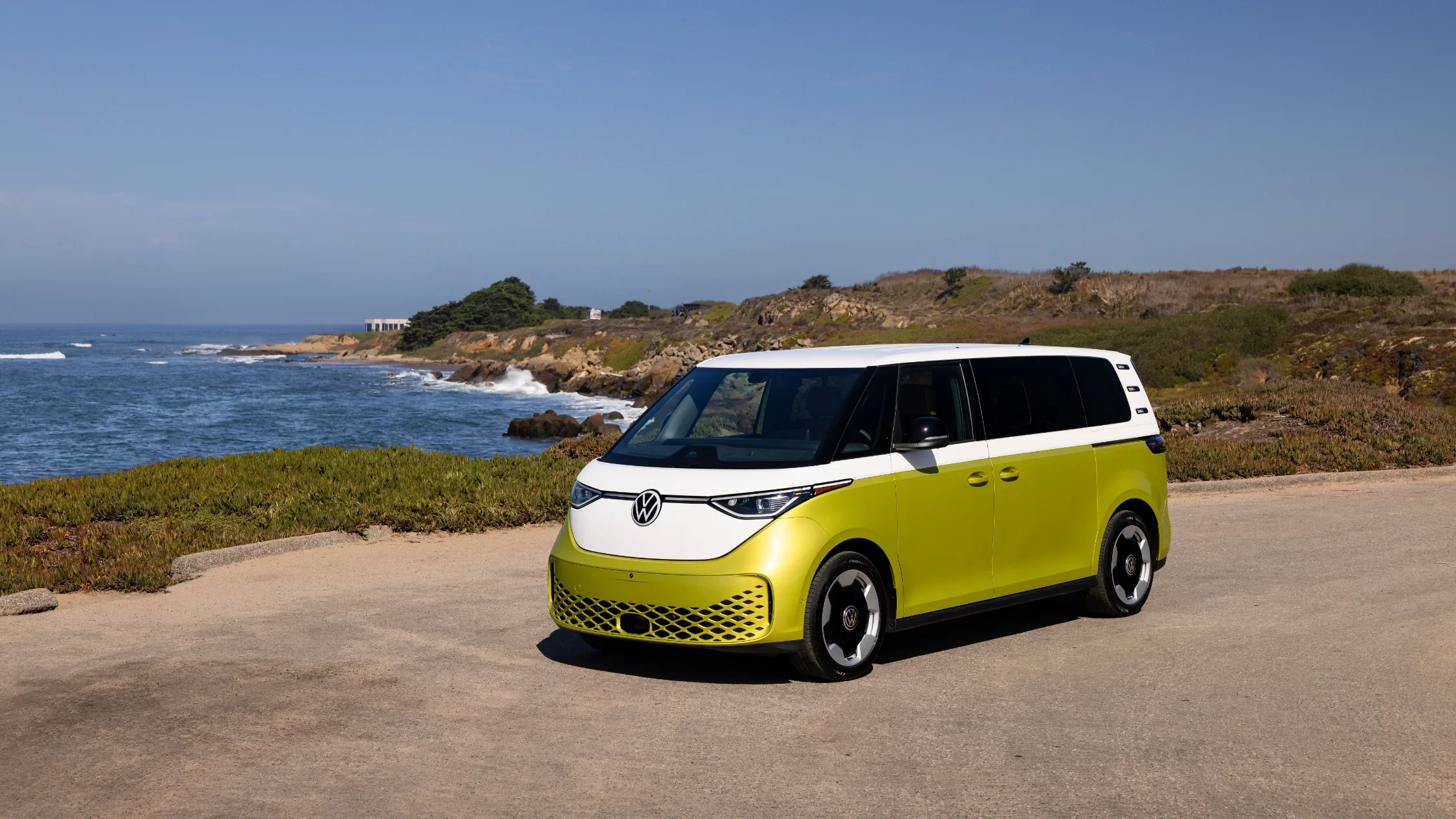 Exterior front and side view of the 2025 Volkswagen ID. Buzz in two-tone lime green by the coast.