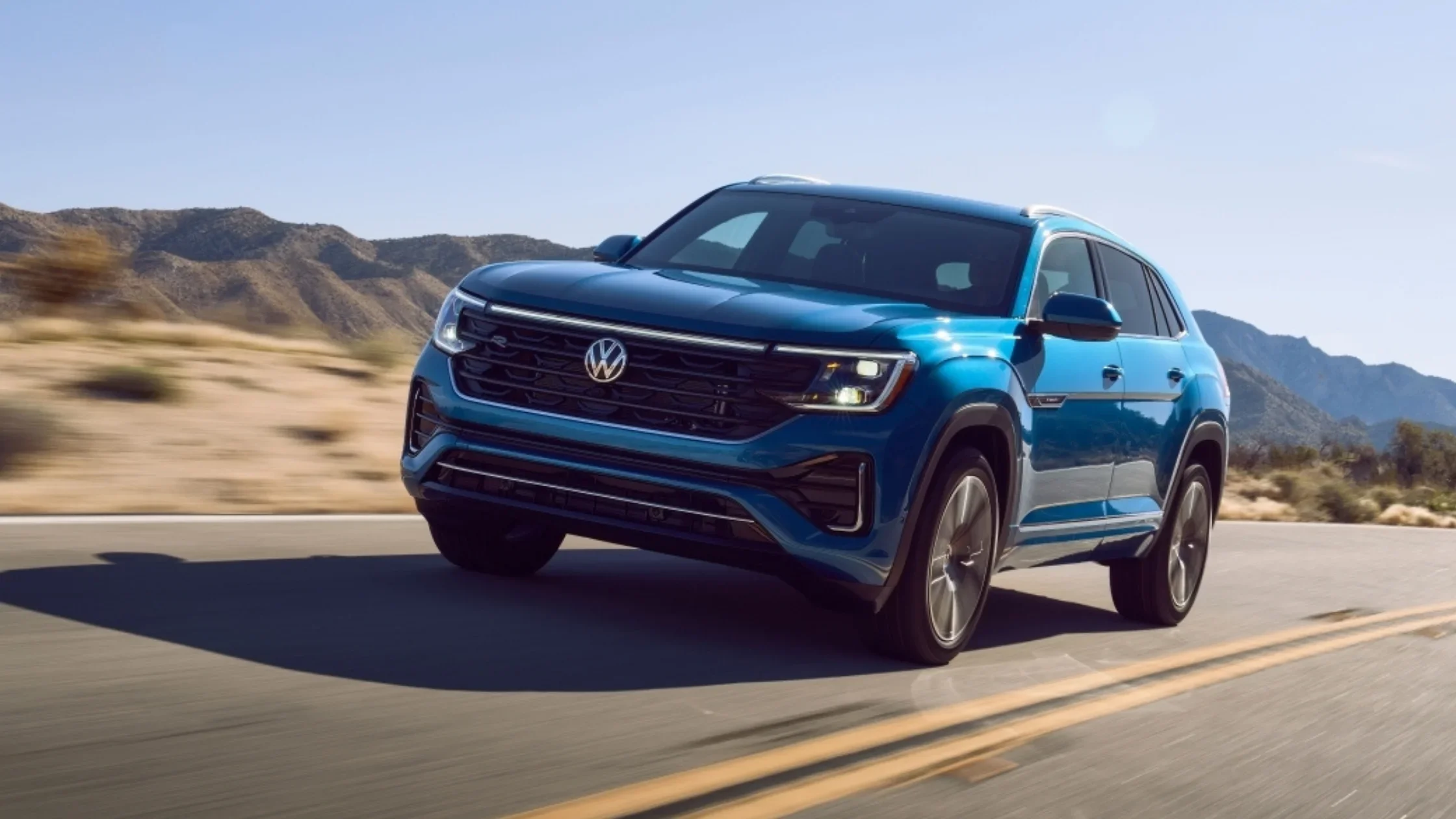 2026 Volkswagen Atlas Cross Sport blue SUV parked in rear three quarter view outside a modern building.
