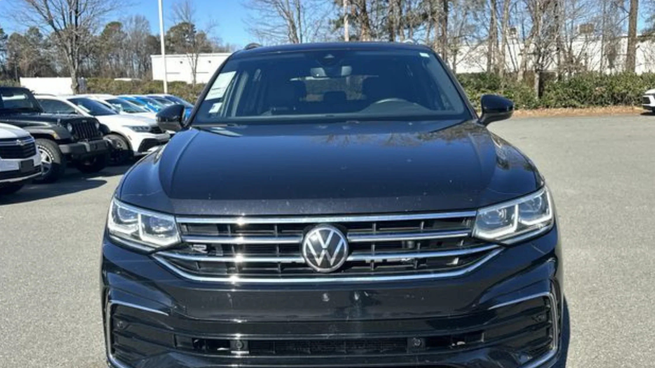 Certified Pre-Owned Volkswagen Tiguan midsize SUV front exterior view with chrome grille parked at dealership.