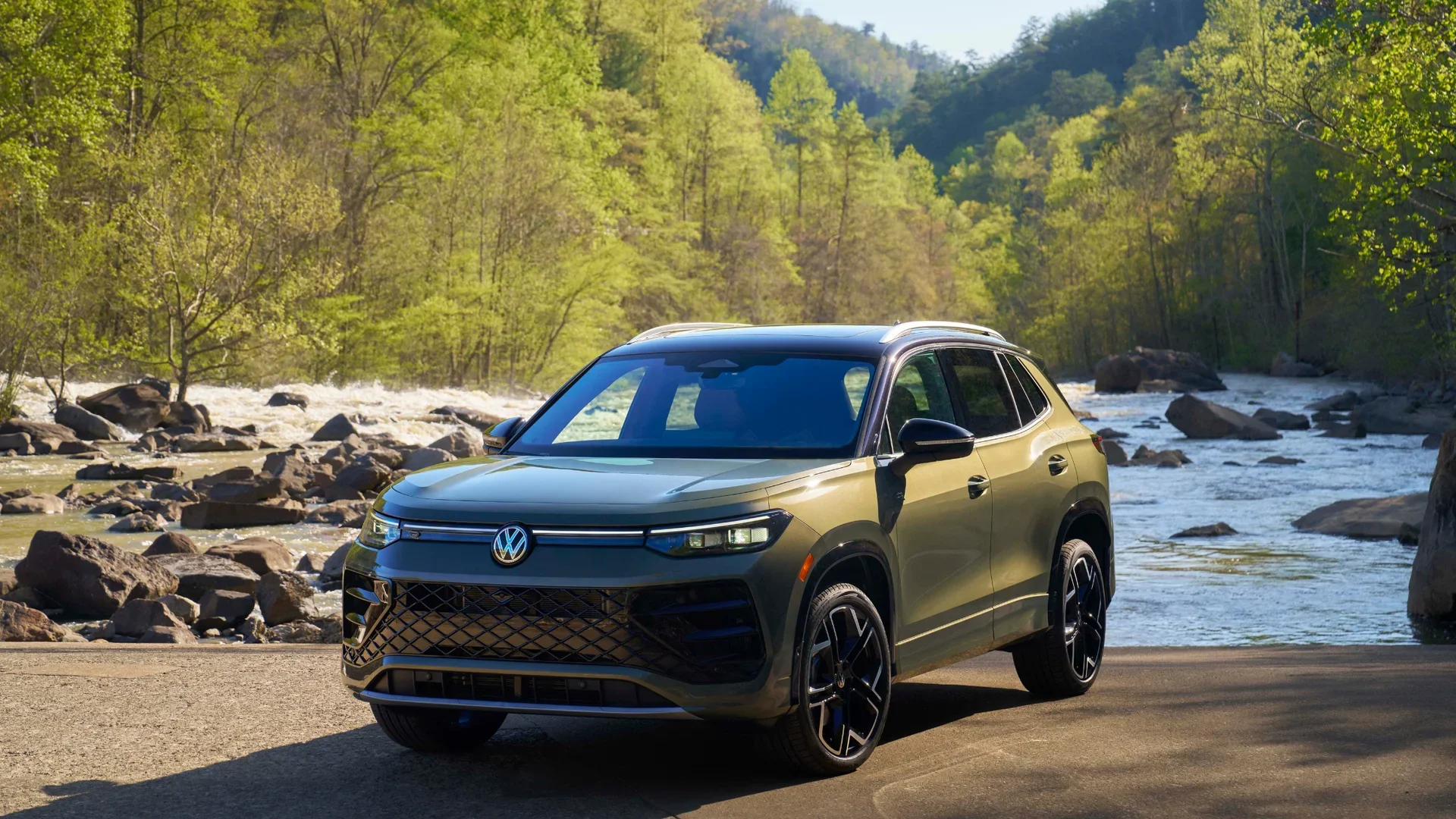 2026 Volkswagen Tiguan SEL R-Line Turbo SUV in blue driving on desert road, sporty front grille and LED lights visible.
